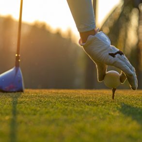 Hand asian woman putting golf ball on tee with club in golf course on evening and sunset time a at Santa Rosa Beach, FL, Golf Courses