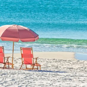 Beach chairs and umbrella by the water on a white sand beach | Blue Mountain Beach Weather