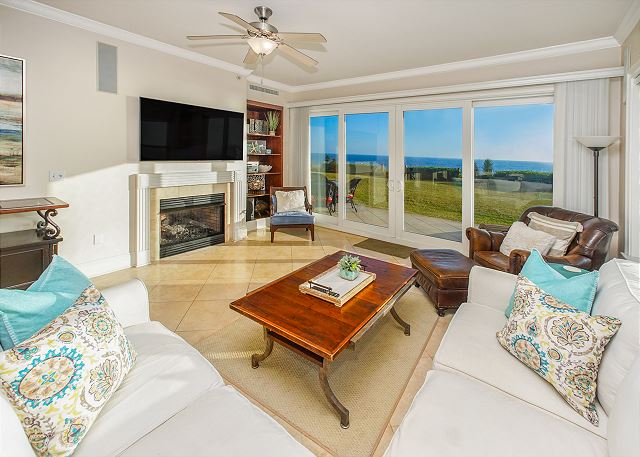 View of the living room with flat screen tv, white couch and ocean view