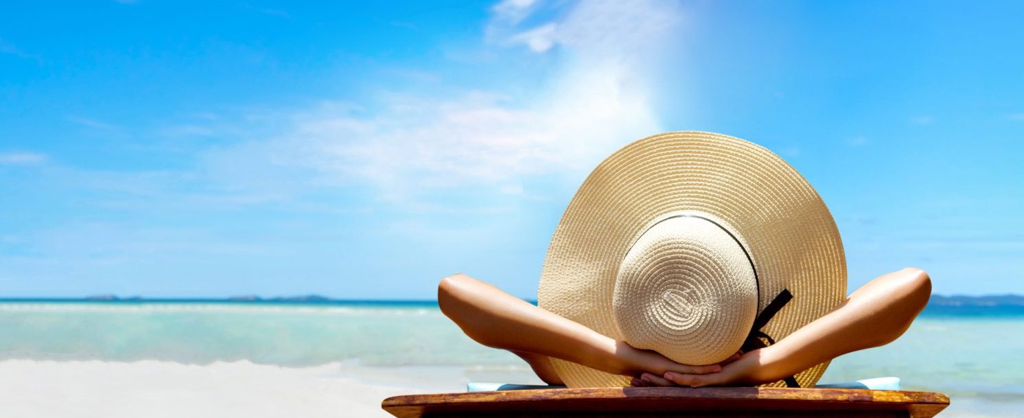 Woman with a hat tanning on a beach | Florida Panhandle Weather in July