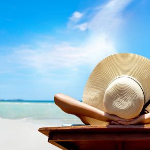 Woman with a hat tanning on a beach | Florida Panhandle Weather in July