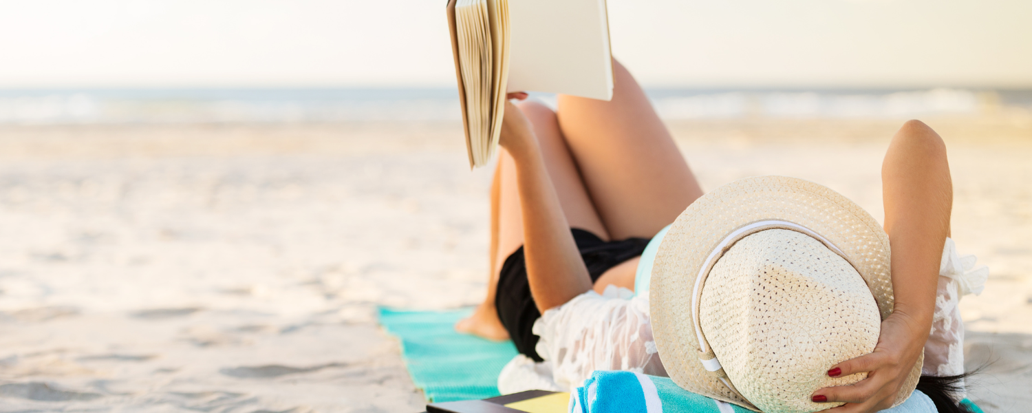 woman laying on beach reading a book