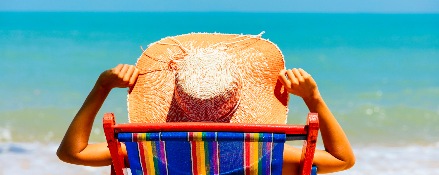 woman with large sun hat laying in beach chair on the beach