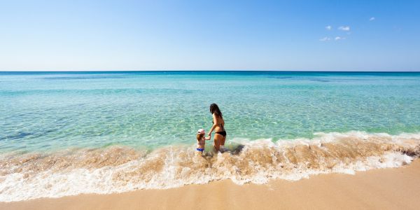 mother and child wading in water at the beach