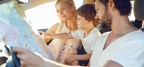 family in car looking at map