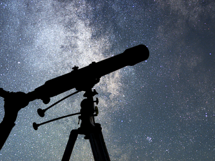 woman with telescope against night sky