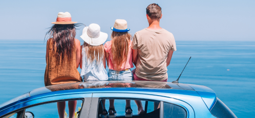 family of four sitting on car overlooking water