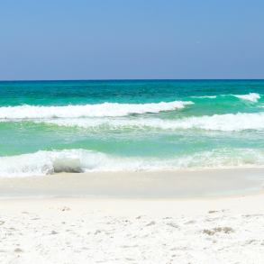white sandy beach with clear blue-green water and waves