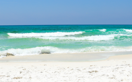 white sandy beach with clear blue-green water and waves