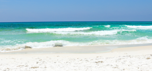 white sandy beach with clear blue-green water and waves