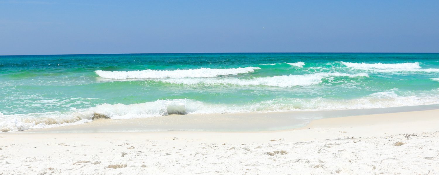 white sandy beach with clear blue-green water and waves