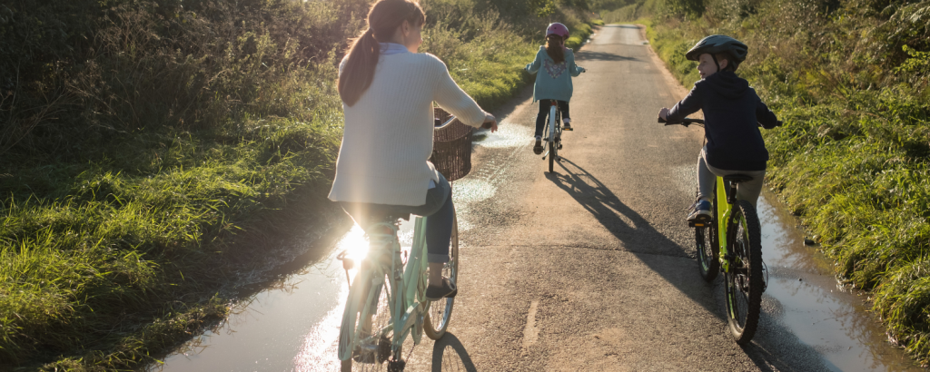 family of three riding bikes on a path
