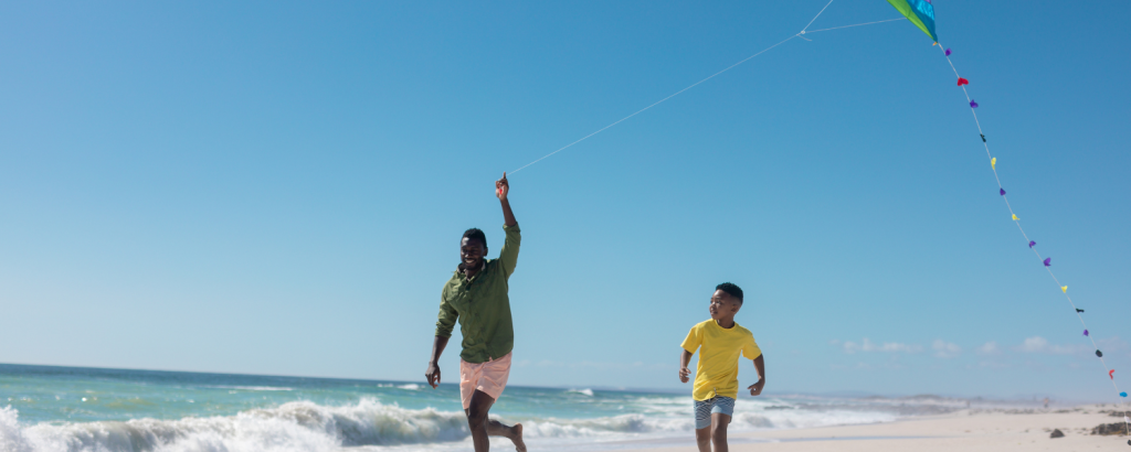 man and boy flying kite on beach