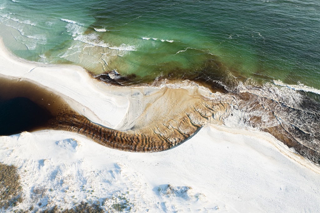 Aerial shot of dune lake flowing into Gulf of Mexico.